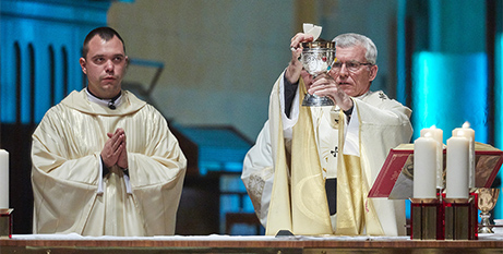Archbishop Timothy Costelloe SDB elevates the Eucharist during the ordination Mass of Fr Grzegorz Rapcewicz (left) at St Mary